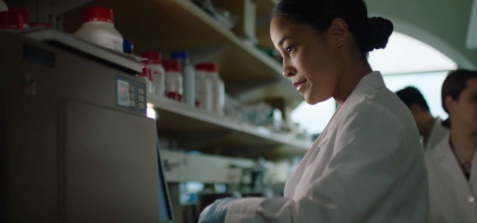 Group of smiling researchers gathered around microscope bench
